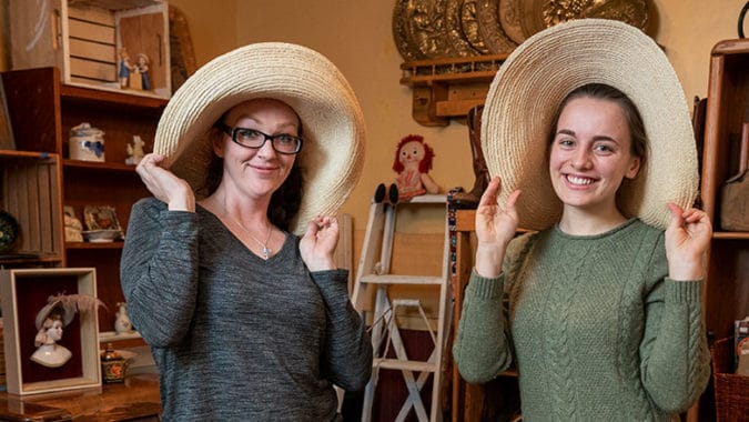 Two women smile for the camera in funny hats.