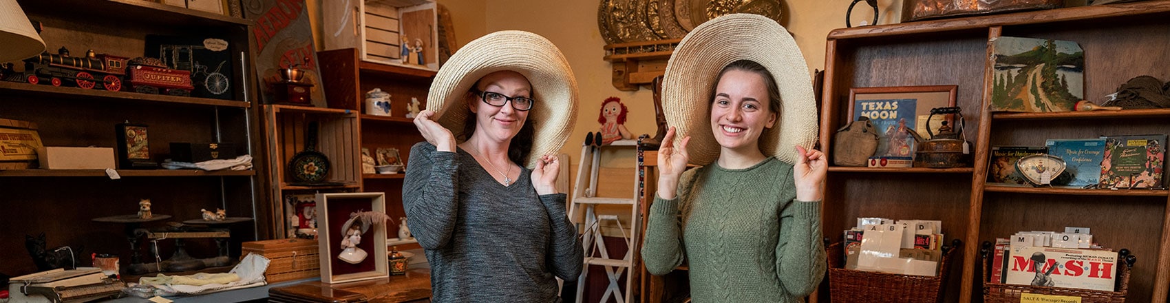 Two women smile for the camera in funny hats.